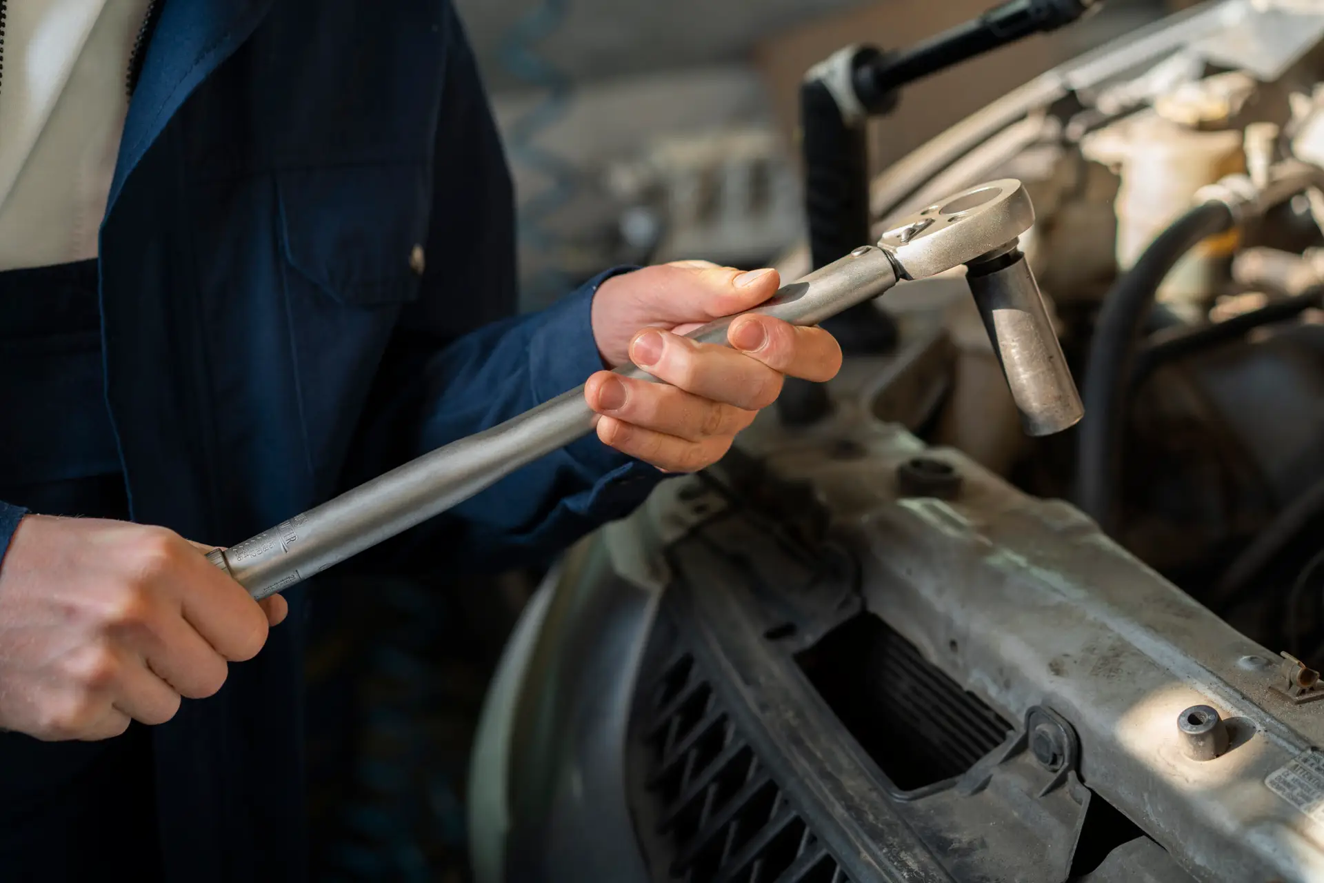 Hydraulic technician using a torque wrench to tighten a hydraulic fitting to manufacturer specification, preventing over-torque damage to the fitting seat and port boss