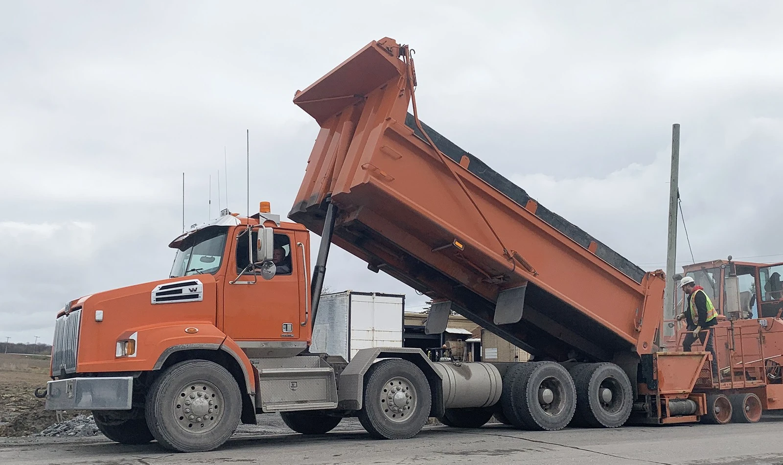 Dump truck with raised bed showing the telescopic single acting hydraulic cylinder fully extended — a classic gravity-return application where the load weight retracts the cylinder when pressure is released